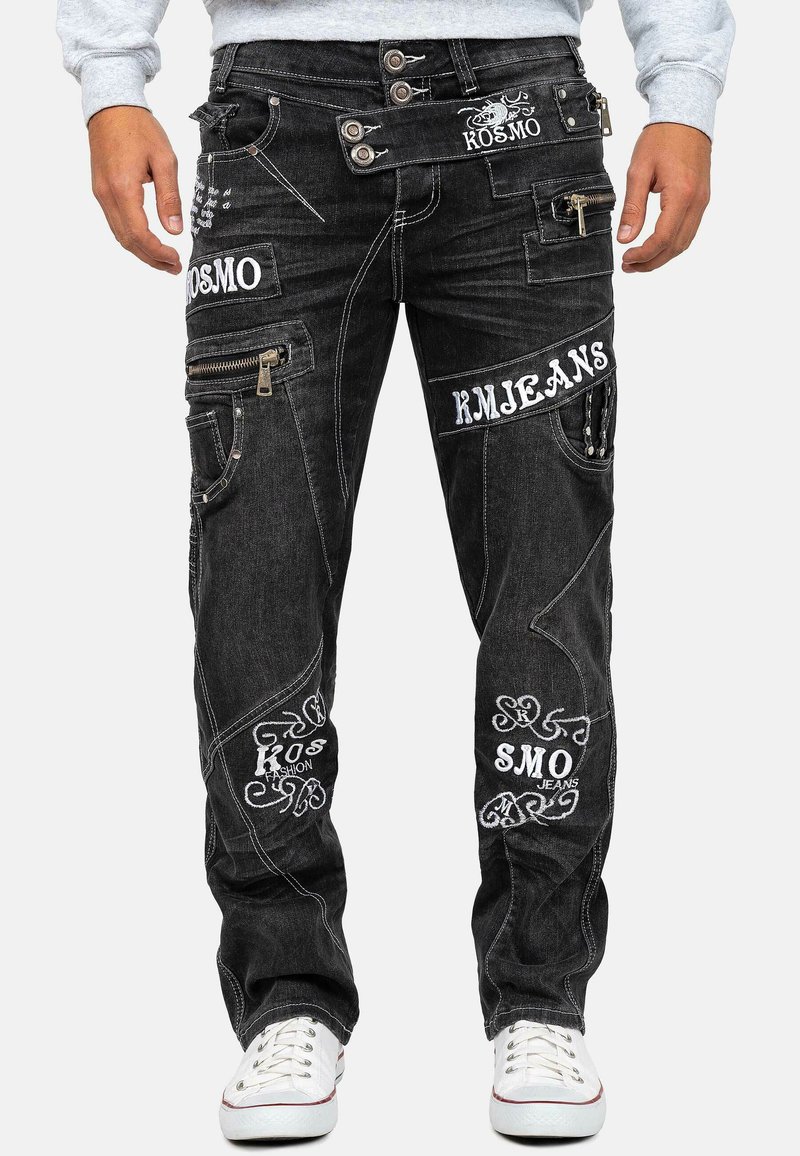 Jeans in denim nero con multiple tasche, zip e testo ricamato bianco. Vestibilità strutturata con dettagli di cuciture decorative.
