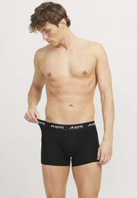Schwarze Boxershorts mit einem breiten elastischen Bund, der den Markennamen "aprel" in Weiß zeigt. Hergestellt aus weichem, elastischem Material, taillierter Schnitt.