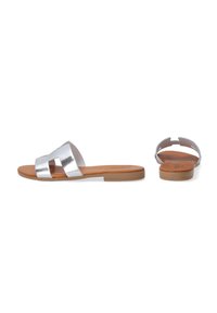 Silver metallic slide sandals with a cut-out design. Features a flat tan sole and a smooth upper material. Minimalist style, open back.