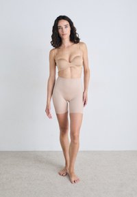Braleta fără cusături și pantaloni scurți cu talie înaltă, realizate dintr-un material elastic. Textură netedă, design minimalist și margini moi.