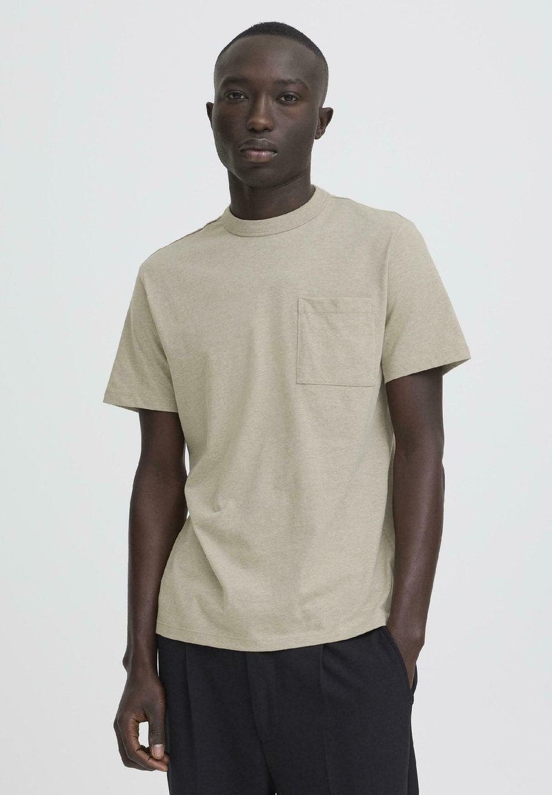 Ανοιχτό χακί κοντομάνικη μπλούζα από βαμβάκι, με στρογγυλή λαιμόκοψη και μια μικρή τσέπη στο αριστερό μέρος του στήθους. Λεία υφή.