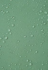 Wodoodporna tkanina w delikatnym zielonym kolorze, z kroplami na teksturowanej powierzchni, podkreślająca jej ochronne właściwości i szczegóły wzornicze.