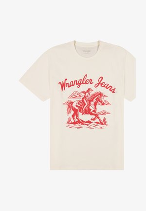 Krém színű póló piros grafikával, amelyen egy cowboy lovagol egy lovon, sivatagi növények, felhők, és a "Wrangler Jeans" felirat látható felette.