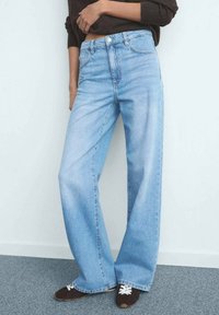 Svetlo modre kavbojke širokih hlačnic iz jeansa; imajo visok pas, raven kroj in klasično pet žepno zasnovo.