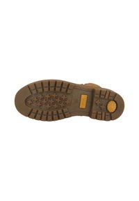 Semelle extérieure en caoutchouc brun avec un motif de grip texturé et un accent central jaune. Présente des crampons en forme de croix pour une traction et une stabilité optimales.