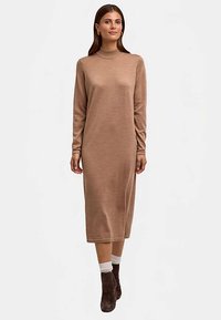 Lange, aangesloten sweaterjurk in lichtbruin, met een hoge hals en lange mouwen, gemaakt van een zachte wolmix, gecombineerd met donkere enkellaarsjes.