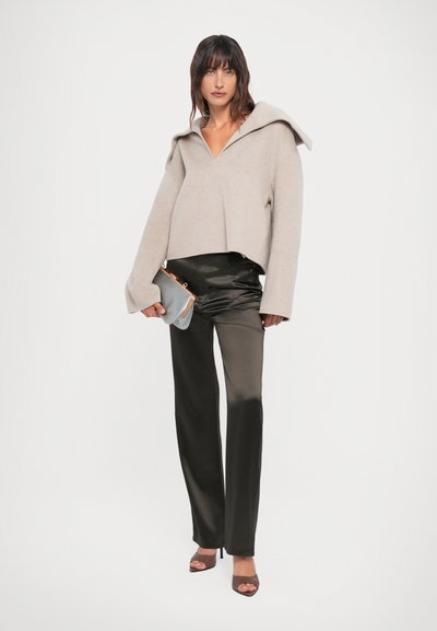 Heledhall hall sweater, mille uksega, mustade satiini laia jala pükstega. Aksessuaarideks on väike, heledhall kott.
