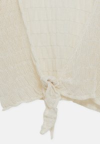 Top a maglia color crema con un design testurizzato a griglia e un dettaglio di nodo anteriore. Tessuto leggero e traspirante.
