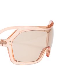 Przerostowe okulary przeciwsłoneczne z przezroczystą, brzoskwiniową oprawą, brązowymi soczewkami o gradientowym odcieniu i geometrycznym wzorem. Posiadają cienkie, zakrzywione zauszniki.