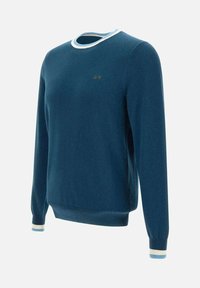 Maglione blu lavorato a maglia con polsini e orlo a coste. Accenti a contrasto bianchi sul colletto e sui polsini. Piccolo logo ricamato sul petto. Design classico con scollatura a girocollo.