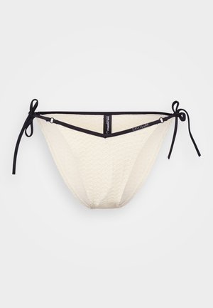 Bikini bottom color crema con un motivo testurizzato, fasce laterali nere con legatura e un design a vita bassa. Presenta una forma triangolare nella parte anteriore.