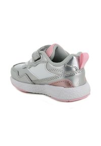 Scarpa sportiva grigia e bianca con dettagli in argento metallico, elementi rosa e una suola bianca testurizzata. Presenta una cinghia con chiusura a velcro.