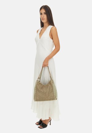 Abito bianco senza maniche con scollatura a V e orlo stratificato. La modella porta una borsa in pelle beige perforata con dettagli verdi e sandali neri con le punte scoperte.