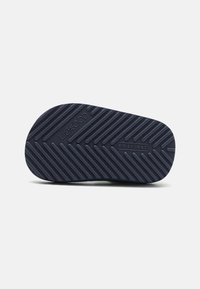 Talpa de pantof de cauciuc de culoare bleumarin, cu un model texturat în zigzag, având detalii de marcă și mărci de dimensiune vizibile pe vârf.