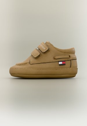 Béžová detská topánočka s dvoma suchými zipsami, značkou Tommy Hilfiger a malou červeno-bielo-modrou vlajočkou na boku.