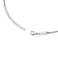 Pulsera de metal plateado con diseño de cadena vinculada, cierre de langosta y una pequeña etiqueta grabada con "BREIL."