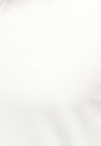 Λευκό ύφασμα με διακριτικό ανάγλυφο κείμενο που αναγράφει "BOSS" στο κέντρο.