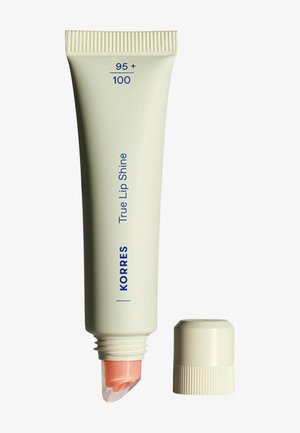 Tube de baume à lèvres Korres True Lip Shine avec le bouchon retiré, montrant le baume couleur pêche à l'intérieur de l'embout applicateur transparent.