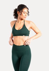 Mörkgrön sport-bh med ribbad textur och justerbara band, kombinerad med högmidjade tights i matchande färg och med subtil märkning.