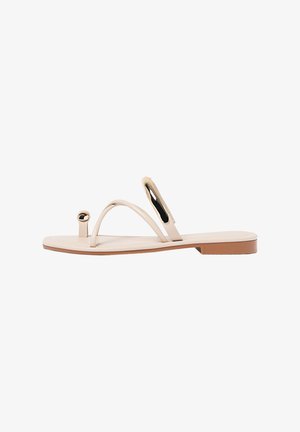 Sandali piatti beige con cinturini sottili, dettagli circolari e una suola liscia. Il design presenta una forma minimalista e una texture lucida.