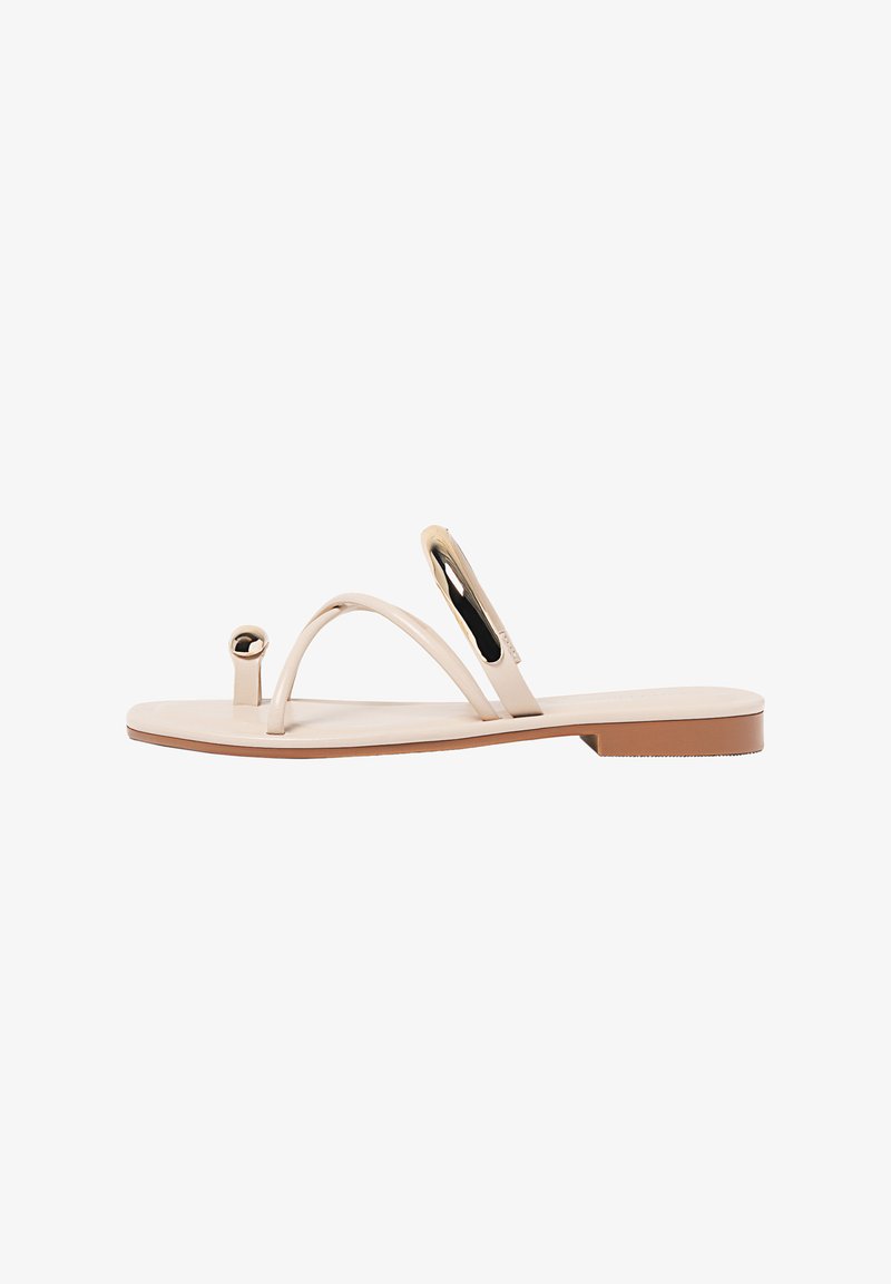 Beige flache Sandalen mit dünnen Riemen, kreisförmigen Details und einer glatten Sohle. Das Design zeigt eine minimalistische Form und eine glänzende Textur.