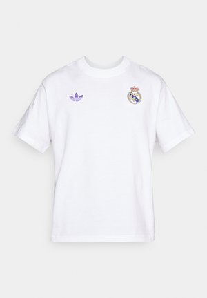 Camiseta de algodón blanca con mangas cortas, con logo morado de Adidas y escudo bordado del Real Madrid en el pecho izquierdo.