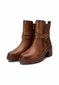 Botas de cuero marrón por el tobillo con cremallera lateral, detalle de hebilla, tacón moderado y suela de goma texturizada. Diseño elegante y funcional.