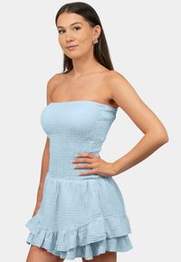 Robe mini sans bretelles, bleu clair, en tissu froissé avec un corsage ajusté et un ourlet volanté. Présente une surface texturée et une coupe évasée.