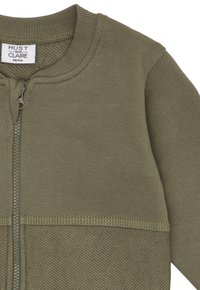 Olivegrüner Baby-Pullover mit geripptem Kragen, Zipper-Front und strukturiertem Strickmuster, Größe 68/6 Monate von Hust und Clare.