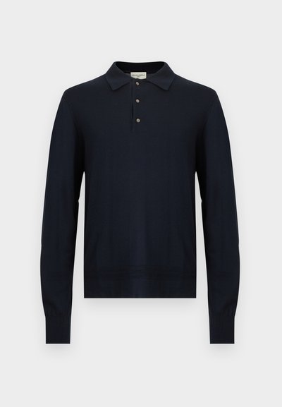 Tumesinist pikka varrukaga polo-särk, millel on kolm nööpi, soonilised varrukaotsad ja klassikaline krae, valgel taustal.