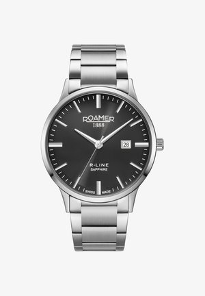 Montre en acier inoxydable avec un cadran noir, des index horaires argentés, un affichage de la date et un bracelet en métal brossé. Nom de la marque à la position 12 heures.