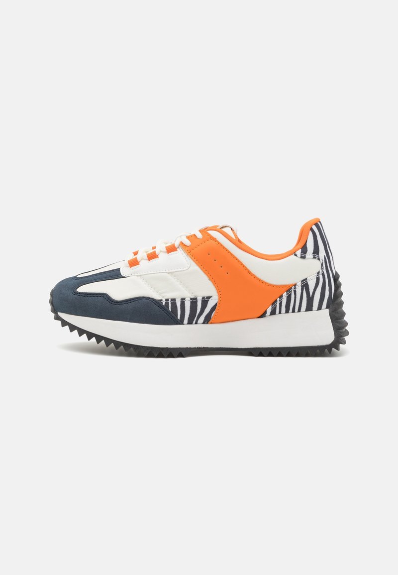 Baskets avec semelle noire, midsole blanche, accents orange, base blanche, bout marine et imprimé zèbre noir et blanc sur le talon et les côtés.