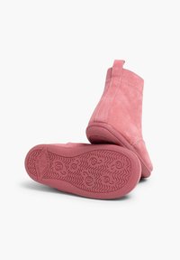 Bottines en suede rose avec une texture lisse, présentant un bout arrondi et une semelle en caoutchouc flexible avec un motif ondulé.