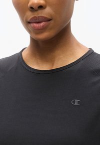 Μαύρο αθλητικό πουκάμισο με υφασμάτινο μοτίβο, στρογγυλή λαιμόκοψη και μικρό, ανάγλυφο λογότυπο στη αριστερή πλευρά. Απαλό ύφασμα, εφαρμοστό σχέδιο.