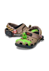 Ghostbusters-inspirierte Crocs in Beige mit schwarzen Löchern und grünen Schleim-Akzenten. Mit einer Slimer-Figur und verstellbaren gestreiften Riemen.