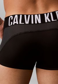 Zwarte boxershorts met een gestructureerde tailleband waarop 'CALVIN KLEIN' in witte letters staat. Gladde stof met een aansluitend ontwerp.