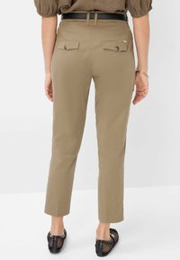 Pantalons khaki au design ajusté, munis d'une ceinture noire, de deux poches arrière avec fermetures à bouton et de jambes fuselées arrivant aux chevilles.