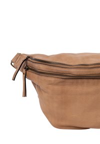 Borsa a cintura in pelle color cuoio con una texture morbida, forma curvata e due scomparti con zip. Presenta tiranti della zip in pelle e una tracolla staccabile.
