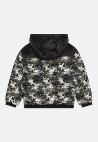 Gepolsterte Jacke mit einer schwarzen Nylonkapuze und Schulterpartie. Camouflage-Muster in Grün, Schwarz und Weiß. Elastische Bündchen und Saum sowie seitliche Taschen.