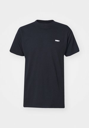 Melnas kokvilnas T-krekls ar īsām piedurknēm un apaļu kakla izgriezumu. Uz kreisās krūtis ir balts "OBEY" logs. Gluda tekstūra.