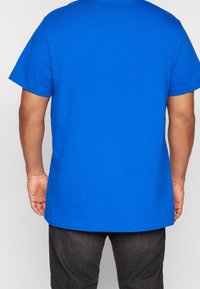 Blå bomulls t-shirt med kort ärm, rund hals och rak skärning. Har en slät yta och inga synliga mönster eller dekorationer.