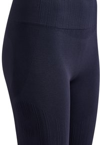 Gros plan sur des leggings bleu marine sans coutures montrant une texture côtelée autour de la taille et des cuisses ainsi qu'un subtil motif en chevron sur la zone des cuisses.