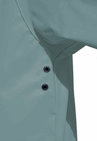 Light teal rain jacket with a smooth, glossy texture, featuring black snap fasteners and visible stitching along the seam.