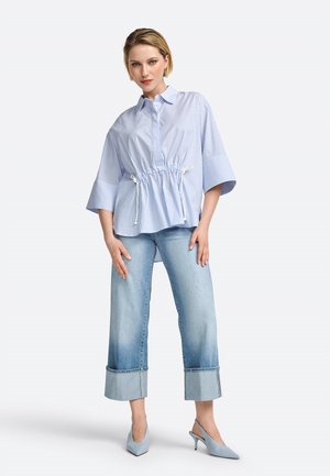 Camicia a righe blu chiaro con vita regolabile, abbinata a jeans a gamba larga blu chiaro con orli risvoltati e scarpe con tacco blu chiaro.