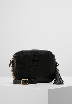 Sac bandoulière en cuir noir granuleux avec boucle dorée, détail de chaîne sur la bandoulière, tirette à pompon et logo embossé à l'avant.
