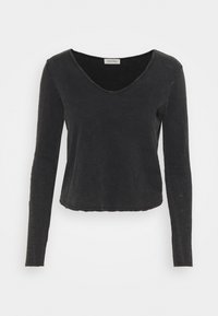 Haut noir à manches longues avec un décolleté en V profond, design cropped, texture douce et finitions à cru. Fabriqué en tissu léger.