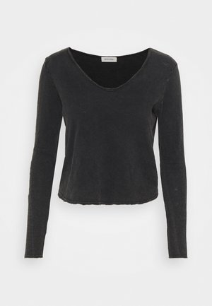 Črna majica z dolgimi rokavi in globokim V-izrezom, kratka zasnova, mehka tekstura in razbrazdani detajli na robu. Narejena iz lahkotnega materiala.