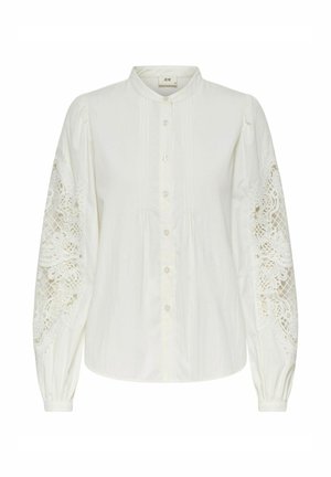 Valge pikkade varrukatega pluus, millel on volangvarrukad ja keerukad pitsidetailid ning nööbid ees. Sile tekstuur ja klassikaline krae disain.