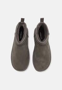 Stivaletti alla caviglia in suede grigio con una morbida fodera interna, punta arrotondata e colletto alla caviglia con anello per una facile vestibilità. Suola testurizzata per una migliore aderenza.