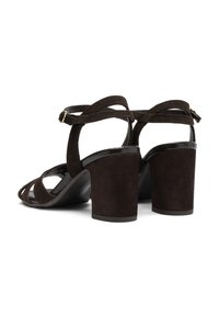 Tamnosmeđi nubuk sandali na visokoj peti s otvorenim prstima, s preklopnim trakama i debelom petom. Uključena podesiva anklet traka.